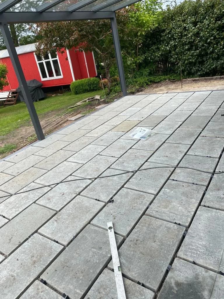 Neu verlegte Terrasse aus großformatigen Natursteinplatten unter einem Glasdach